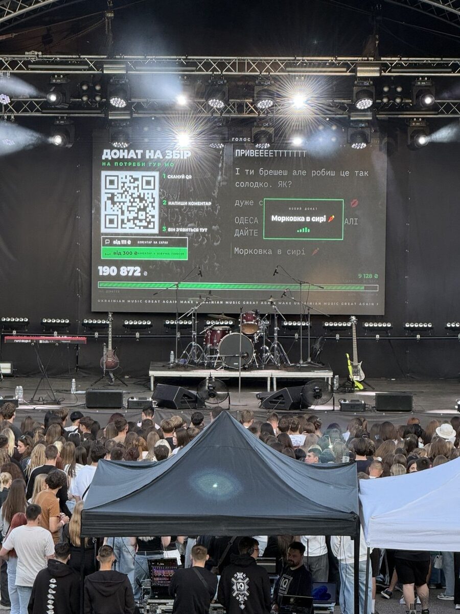 Festival stage LED screen showing live crowd messages, the QR code and the goal bar